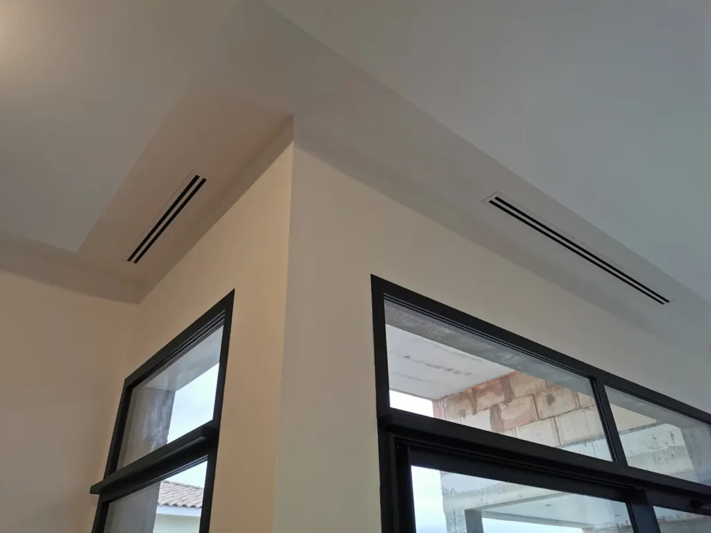 Grilles de soufflage linéaires d’une clim gainable intégrées au faux plafond d’un séjour