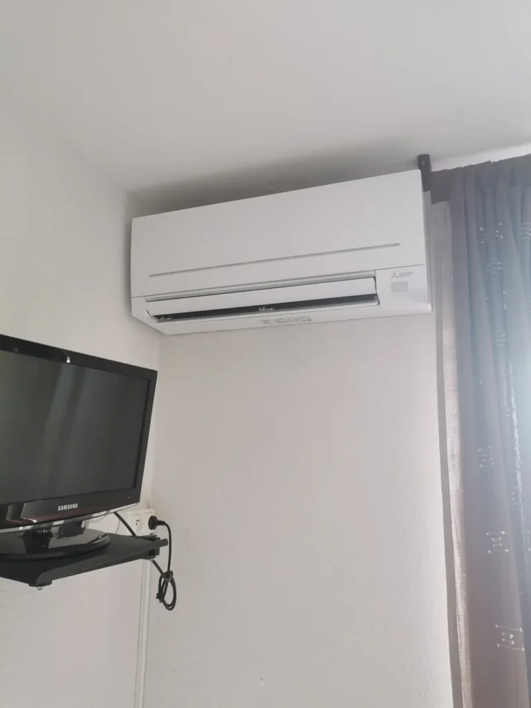 Clim murale blanche installée au-dessus d’un meuble TV dans un salon