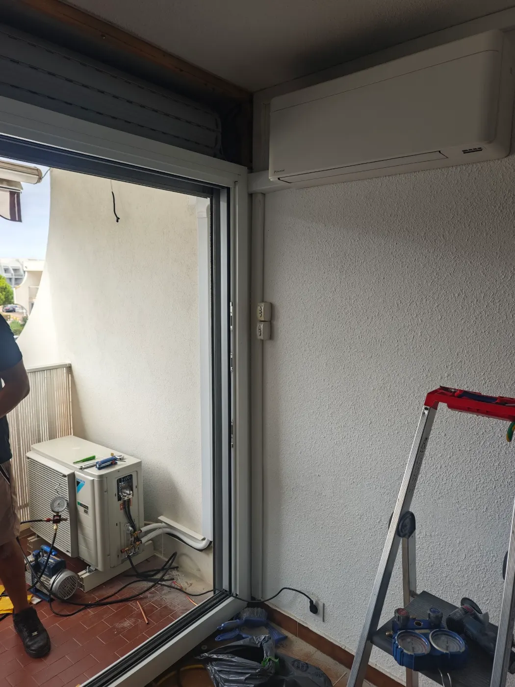 Unité extérieure de clim réversible installée au sol d’un balcon