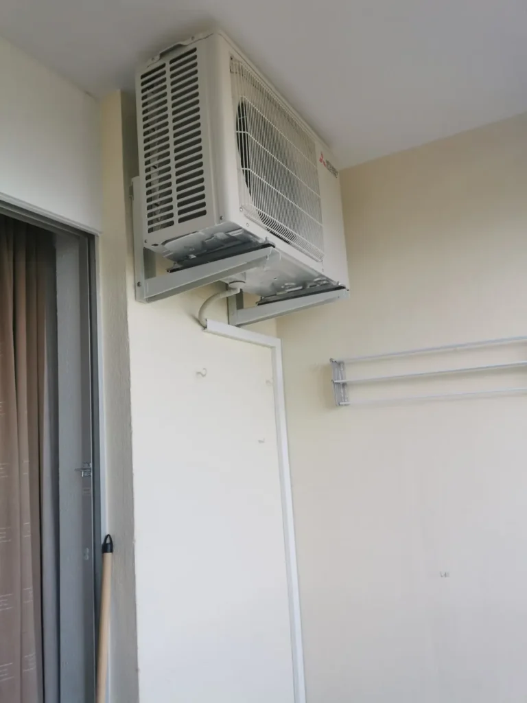 Unité extérieure de climatisation fixée en hauteur dans la loggia d’un logement en copropriété