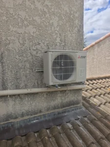 Unité extérieure Mitsubishi Electric fixée en façade au-dessus d’une toiture
