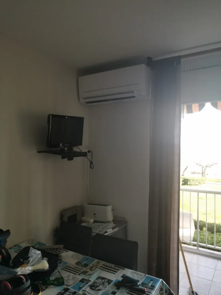 Climatisation murale en fonctionnement dans un séjour près de la baie vitrée