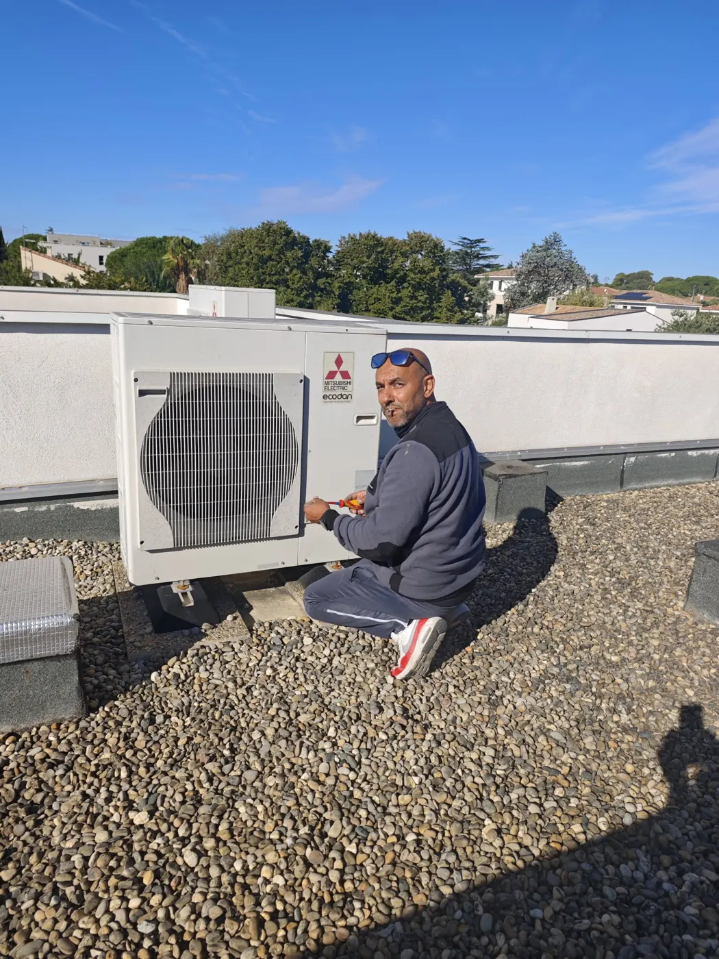 Technicien Solar&Clim branchant une unité extérieure Mitsubishi Electric sur un toit terrasse
