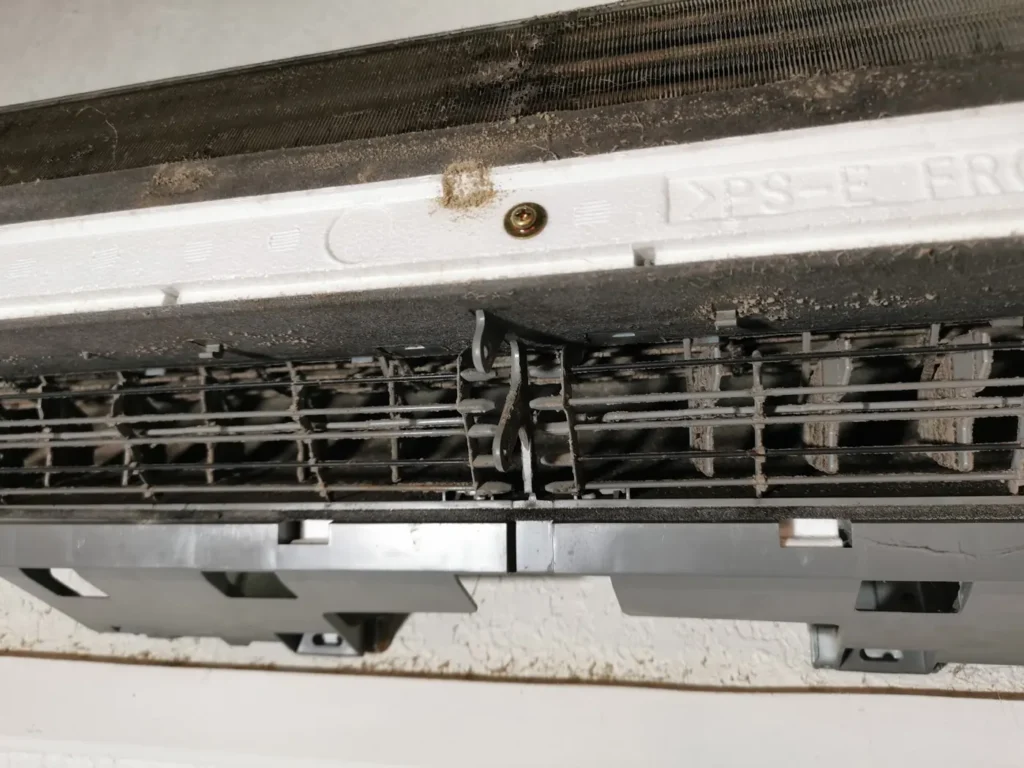 Unité intérieure ouverte avant désinfection de la clim : volets et grille de soufflage démontés