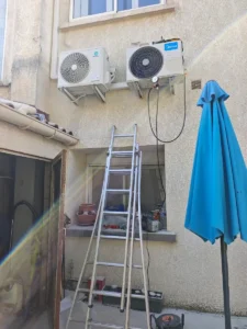 Deux unités extérieures de climatisation fixées en façade au-dessus d’une terrasse, près des fenêtres voisines