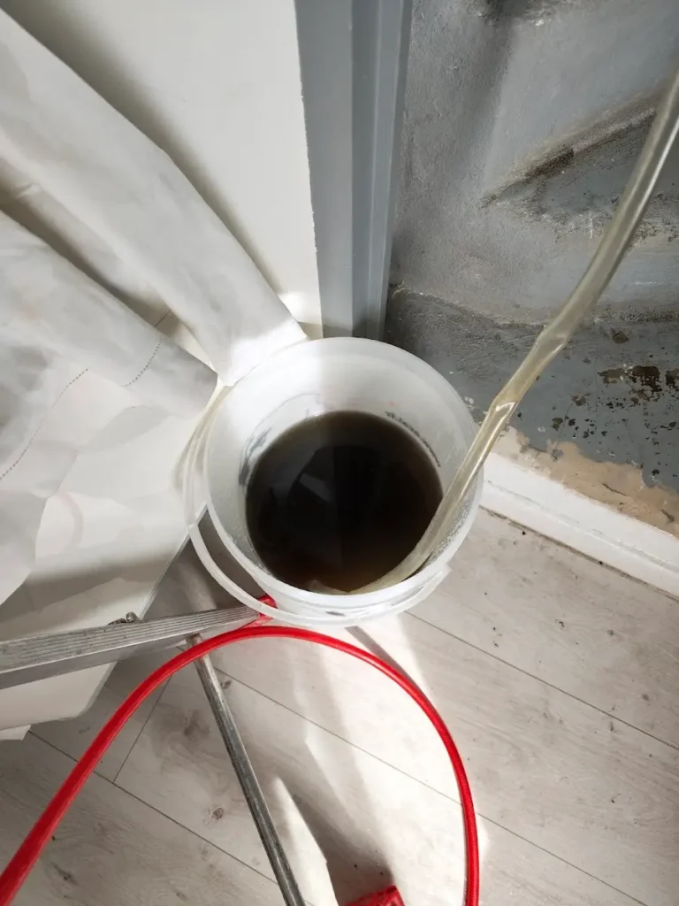 Seau d’eau noircie récupérée pendant le lavage d’une unité intérieure de climatisation encrassée