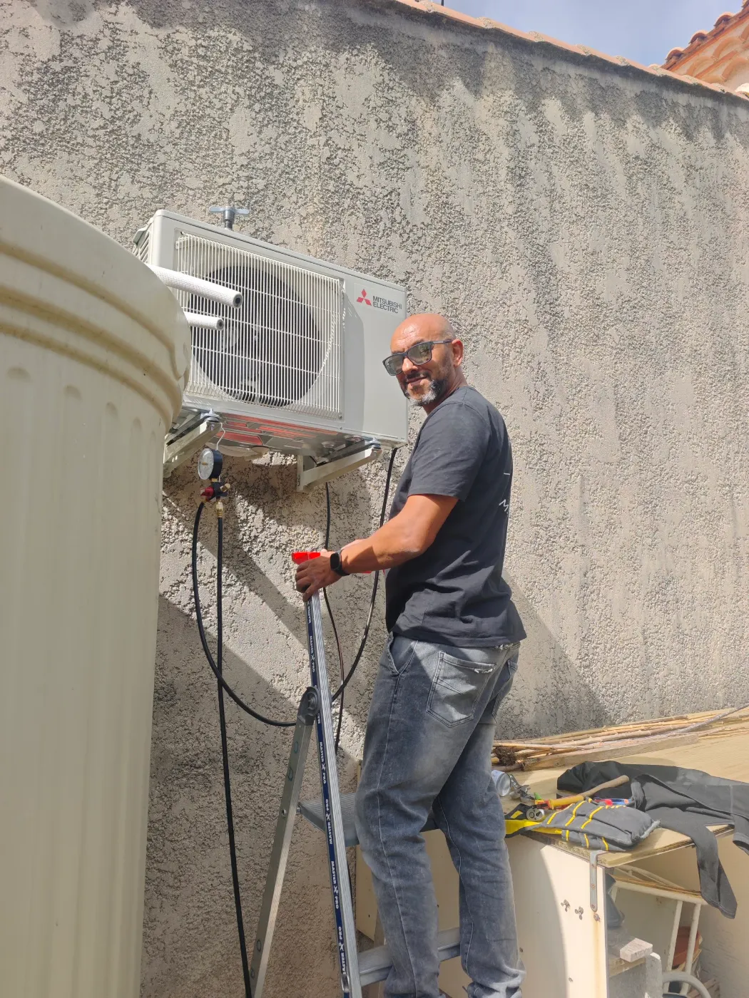 Frigoriste Solar&Clim contrôlant une unité extérieure au pied d’un bâtiment
