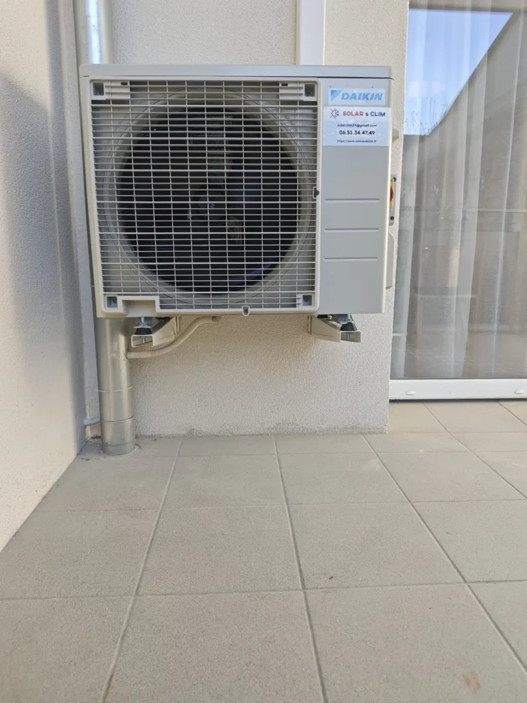 Unité extérieure de clim réversible posée sur supports au sol d’une terrasse