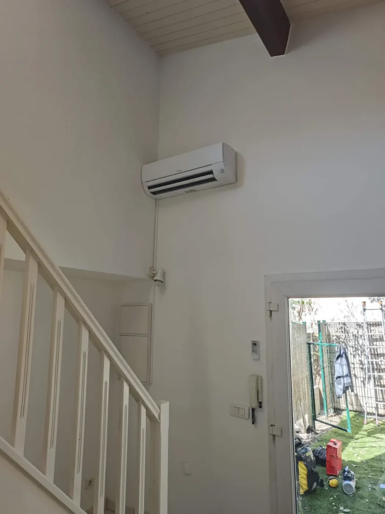 Split mural installé en hauteur dans l’entrée d’une maison, près de l’escalier