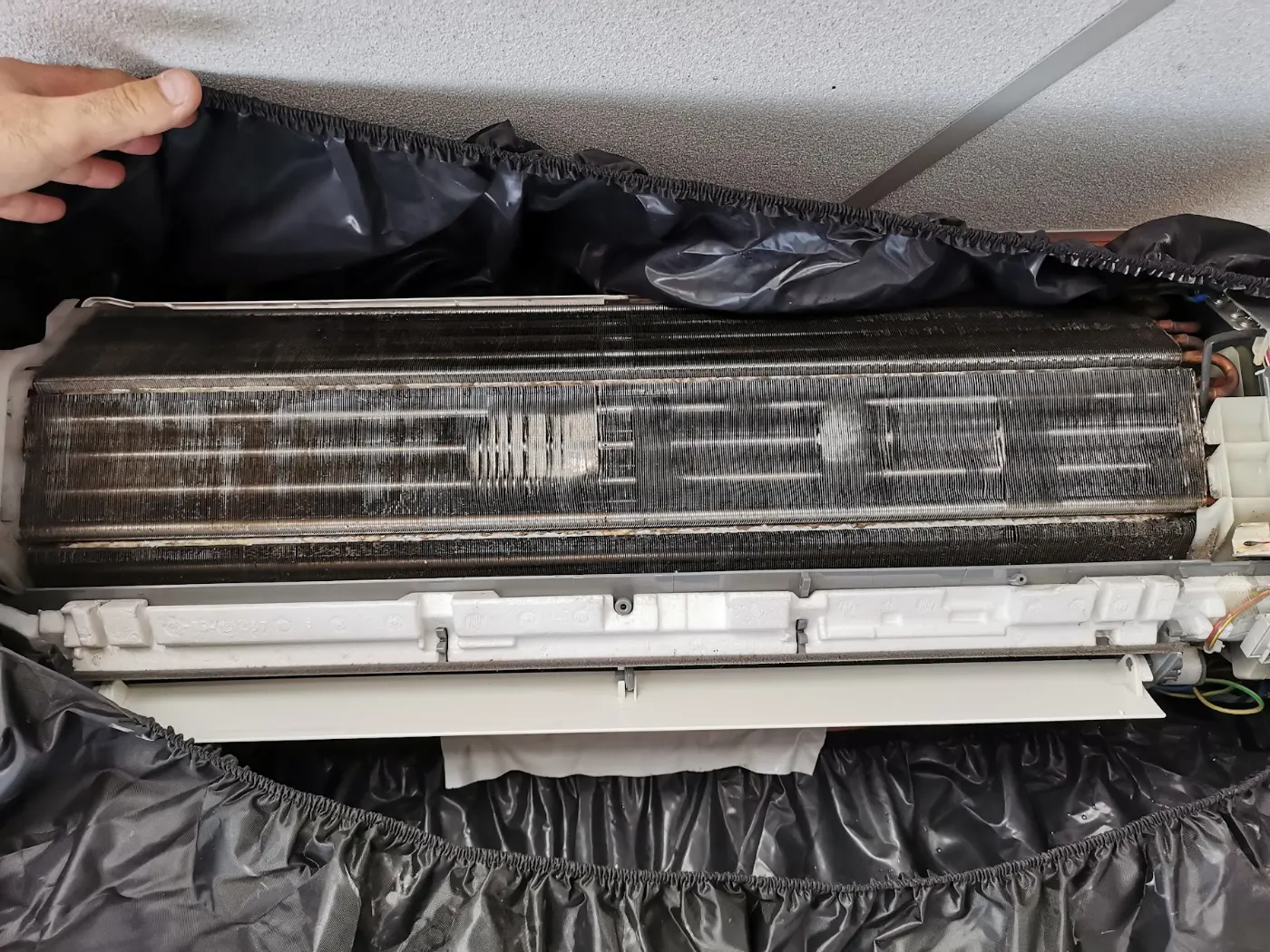 Unité intérieure encrassée sous bâche de protection avant son nettoyage