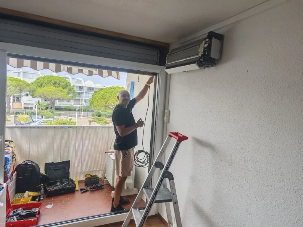 Pose d’une climatisation réversible au-dessus d’une baie vitrée par un technicien Solar&Clim