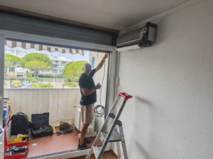 Pose d’une climatisation réversible au-dessus d’une baie vitrée par un technicien Solar&Clim