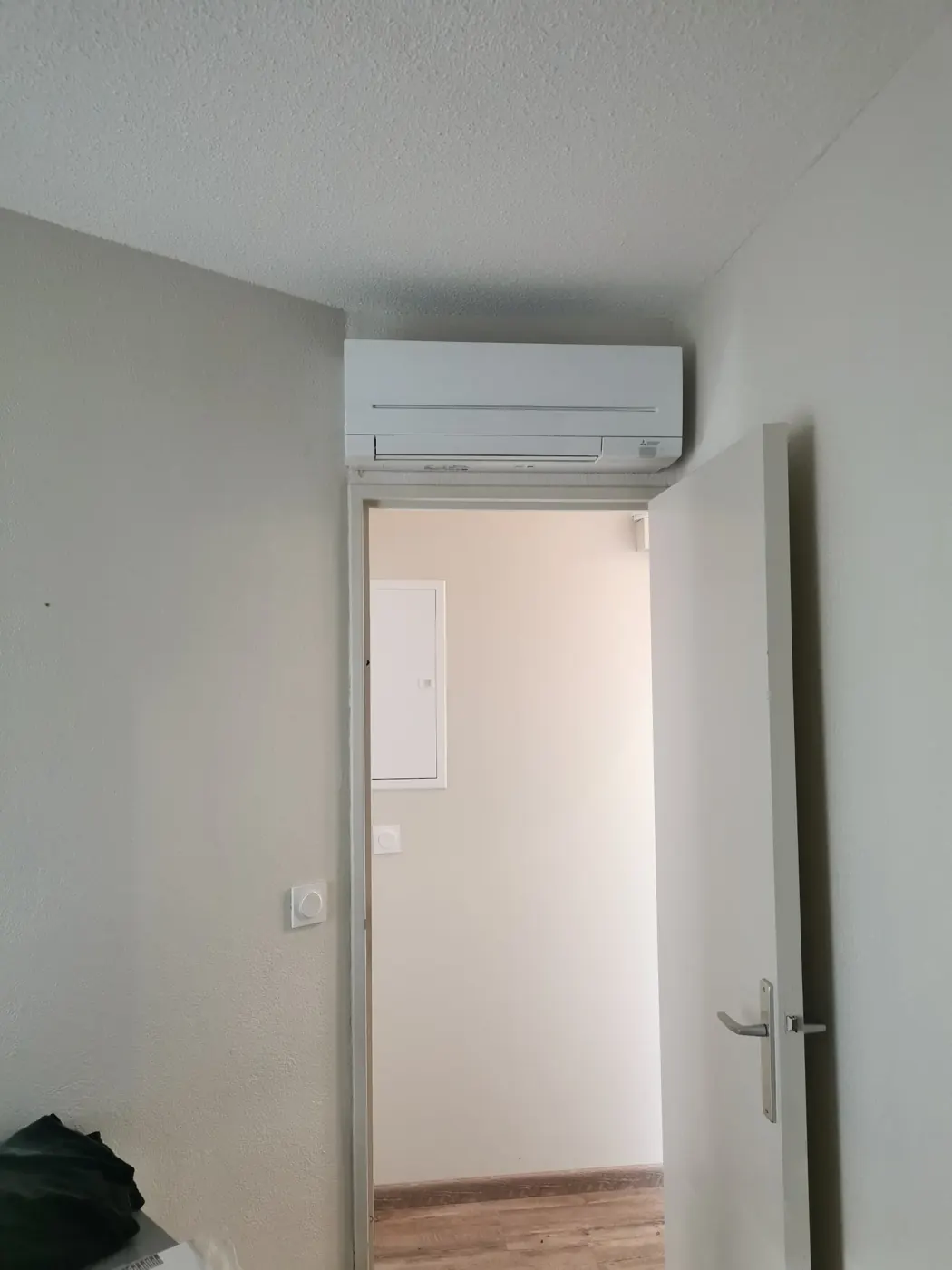 Unité murale de clim posée au-dessus d’une porte pour rafraîchir le couloir en été
