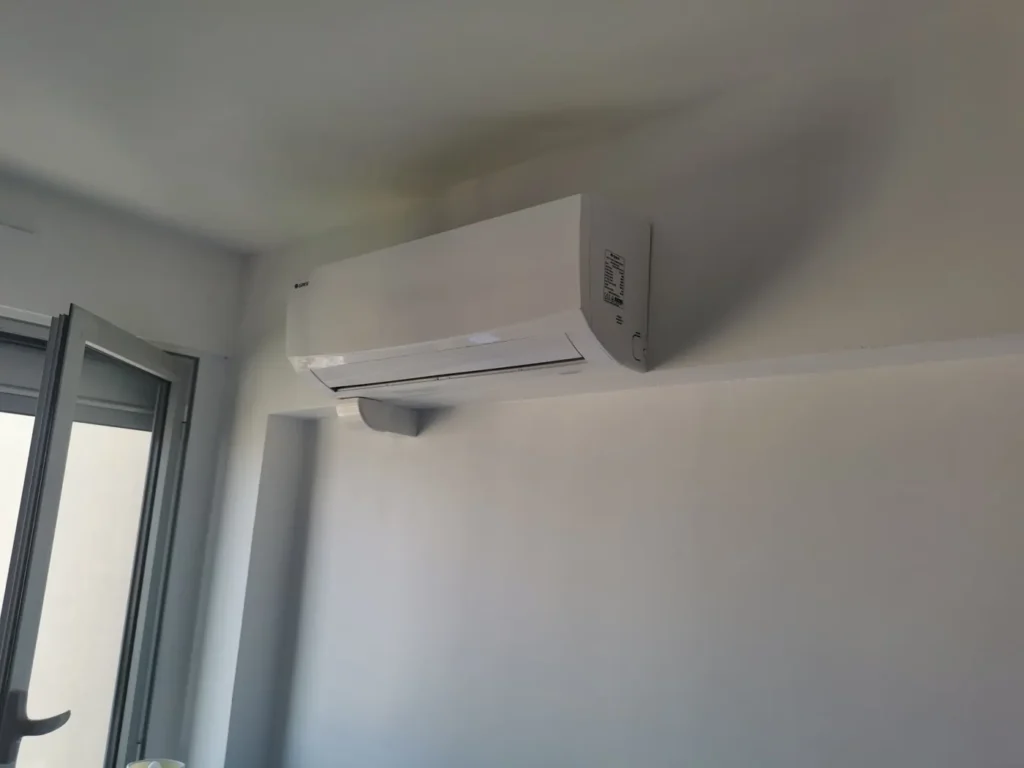 Split mural de climatisation réversible posé en angle au-dessus d’une porte-fenêtre