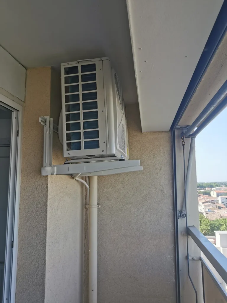 Unité extérieure de climatisation sur console murale dans l’angle d’un balcon d’immeuble