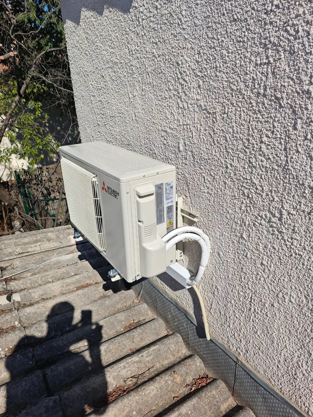 Unité extérieure de climatisation posée sur une toiture en tuiles