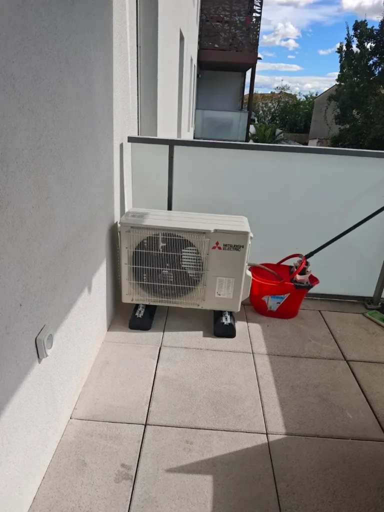 Unité extérieure Mitsubishi Electric posée sur la terrasse d’un appartement, derrière le garde-corps