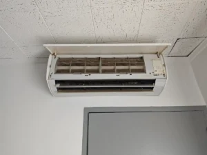 Unité murale de climatisation ouverte pour entretien dans un local professionnel à faux plafond en dalles